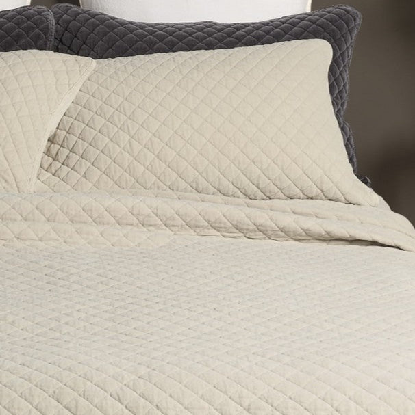 Foulard de lit matelassé crème Dove, couture en losanges, sur le lit