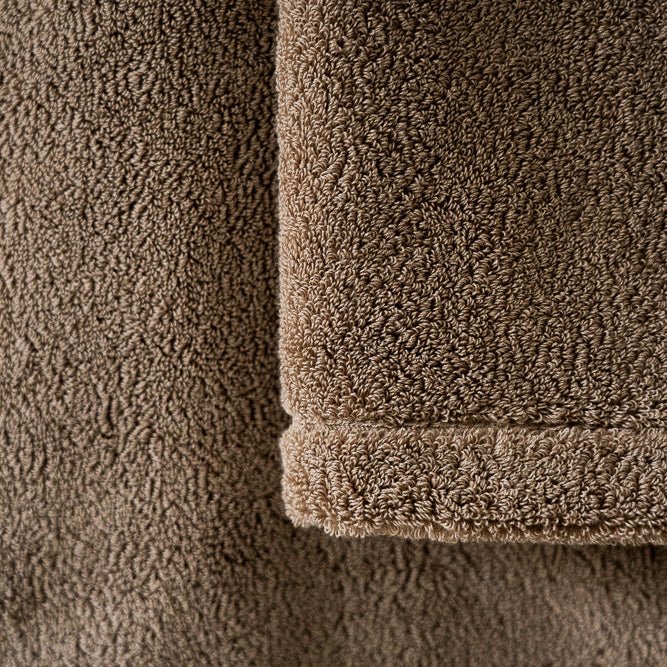 Serviette en coton beige, gros plan sur la surface éponge et la bordure