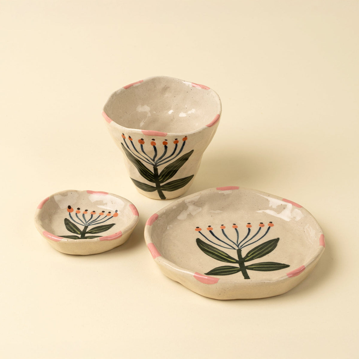 Ensemble tasse et petits bols en grès beige, motif lotus vert, liserés roses.