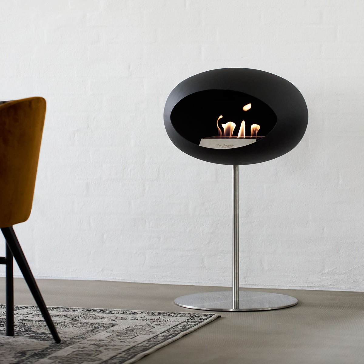 Foyer au bioéthanol Le Feu Steel Low noir avec dôme en acier mat, design scandinave moderne et flamme réelle pour intérieur contemporain.
