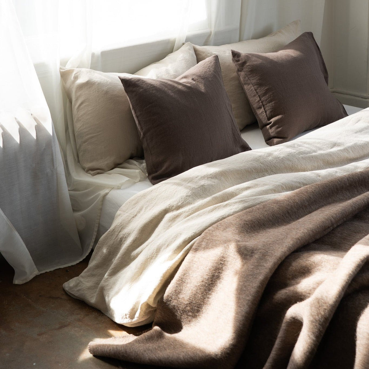 Jeté en laine brun sur canapé-lit, drapé sur une couette et coussins
