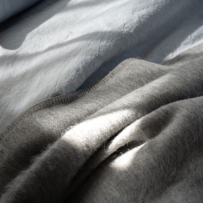 Jeté en laine gris clair, bord à finition tissée, texture duveteuse