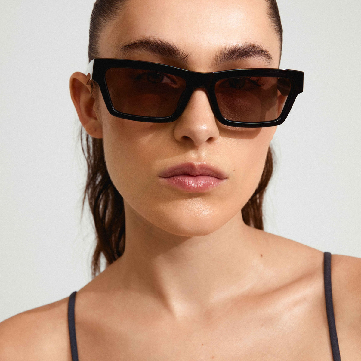 Lunettes de soleil ASHLYN noires portées, monture angulaire et verres teintés.