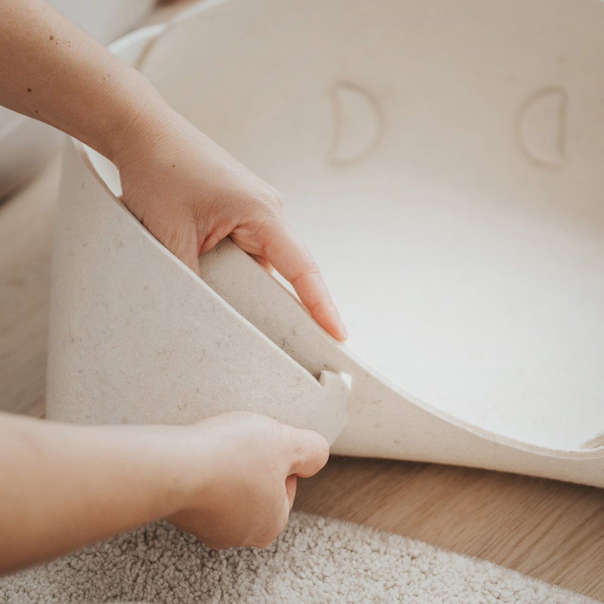 Assemblage du panier en feutre de laine beige, mains ajustant le bord