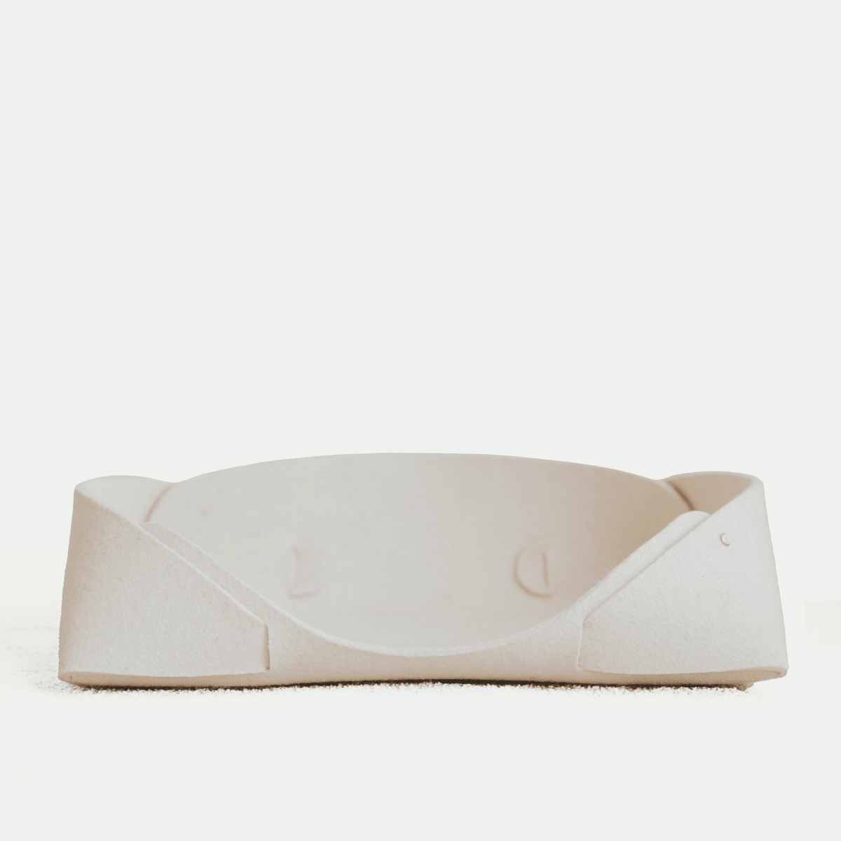 Panier pour animaux en feutre de laine clair, bords arrondis et intérieur rembourré.