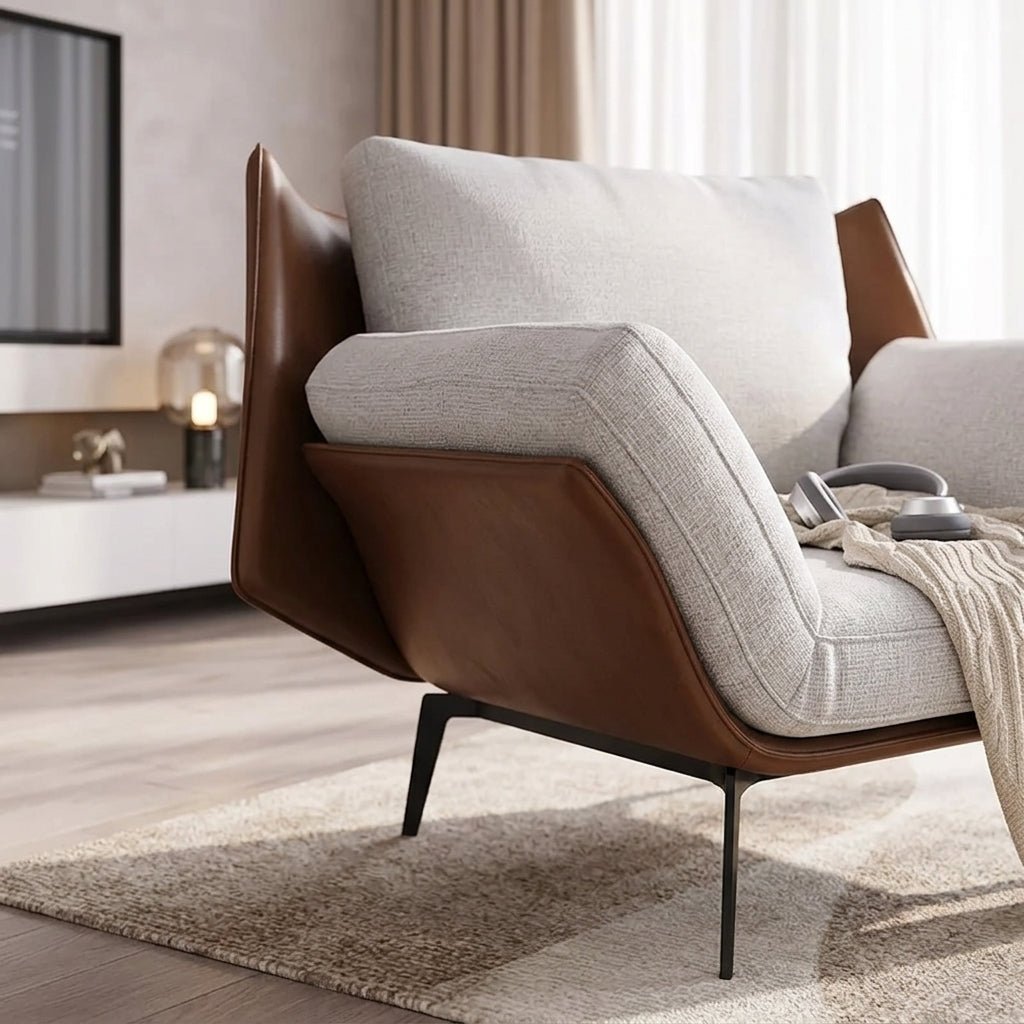 Fauteuil d’appoint gris en tissu, vue latérale : accoudoir et base marron en cuir.