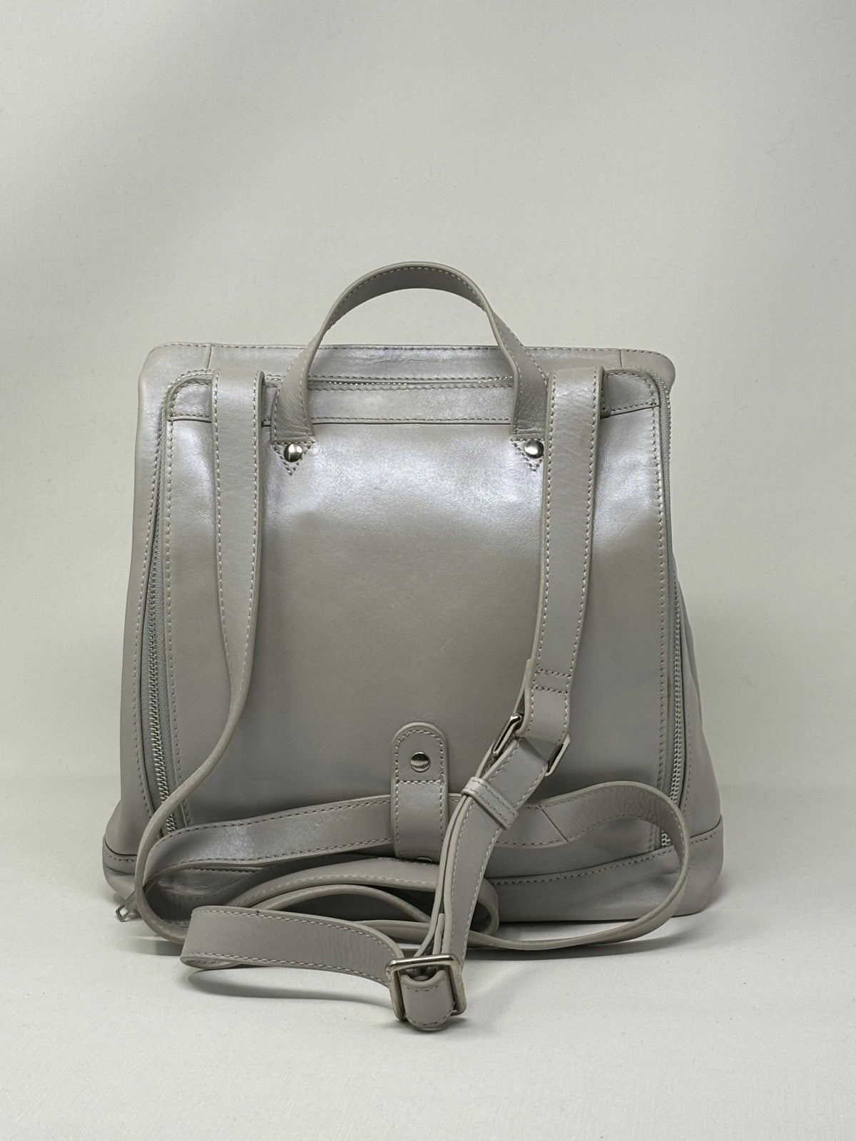 Sac à dos en cuir argent, vue arrière avec bretelles réglables et fermetures latérales.