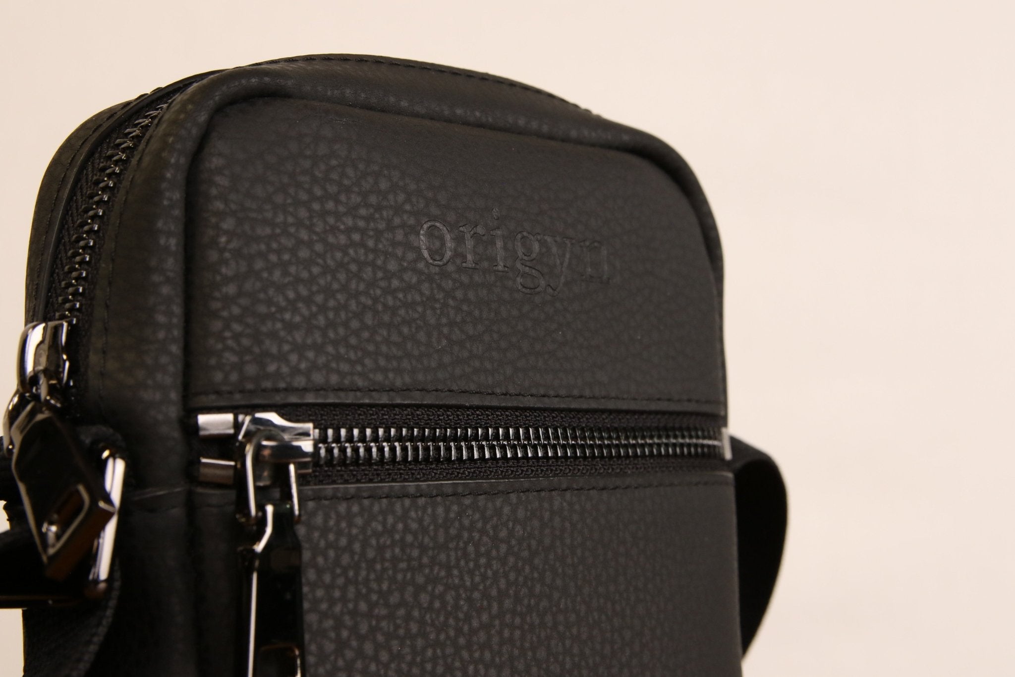Sac bandoulière noir en cuir végétal, gros plan sur fermeture éclair et logo
