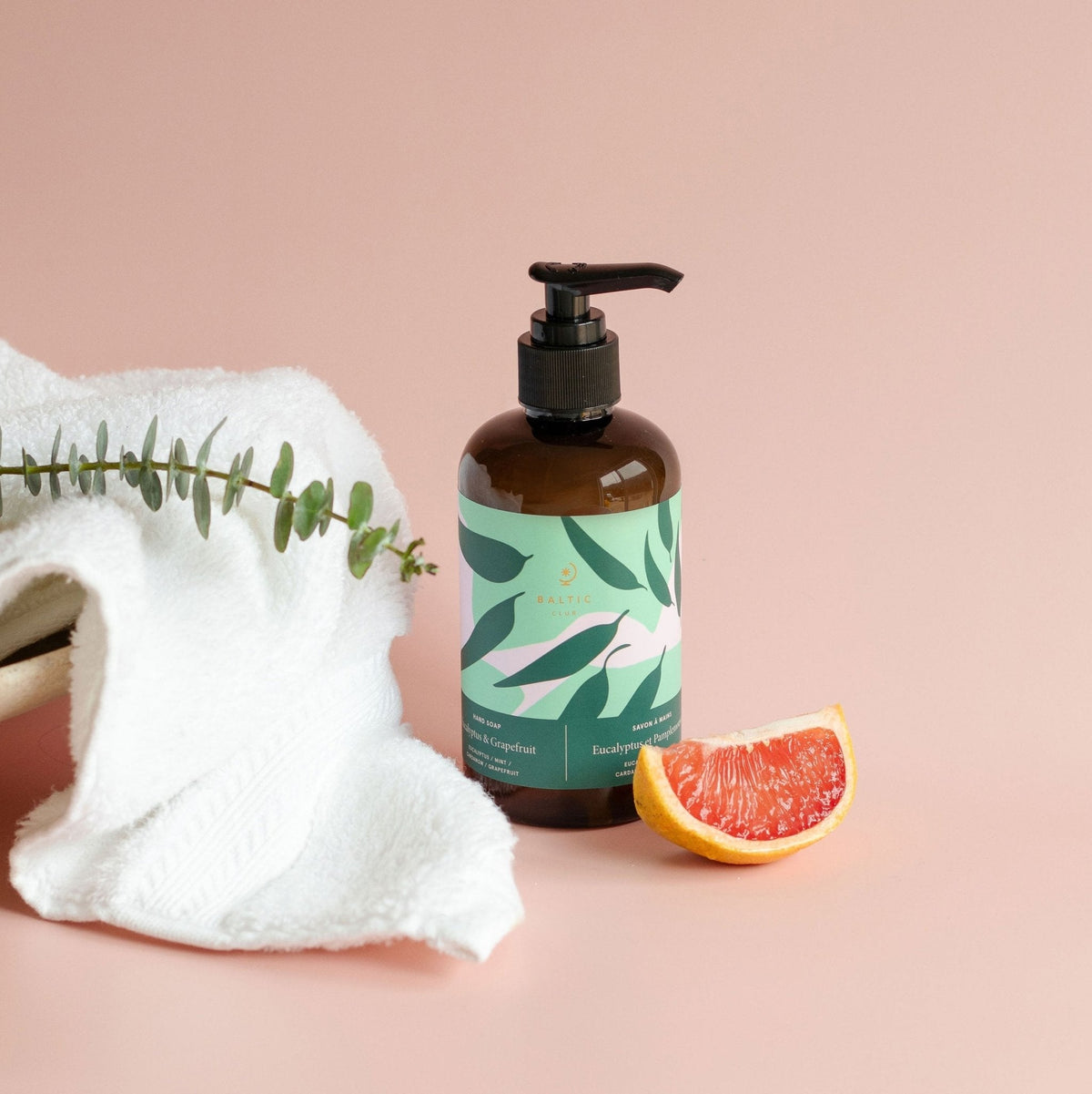 Savon à mains liquide en flacon brun avec pompe noire et tranche de pamplemousse