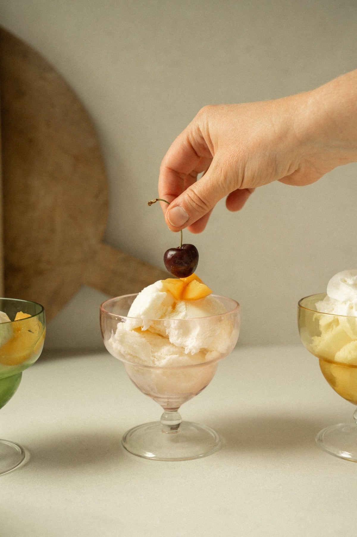 Coupe en verre rose à pied remplie de dessert blanc et garniture orange