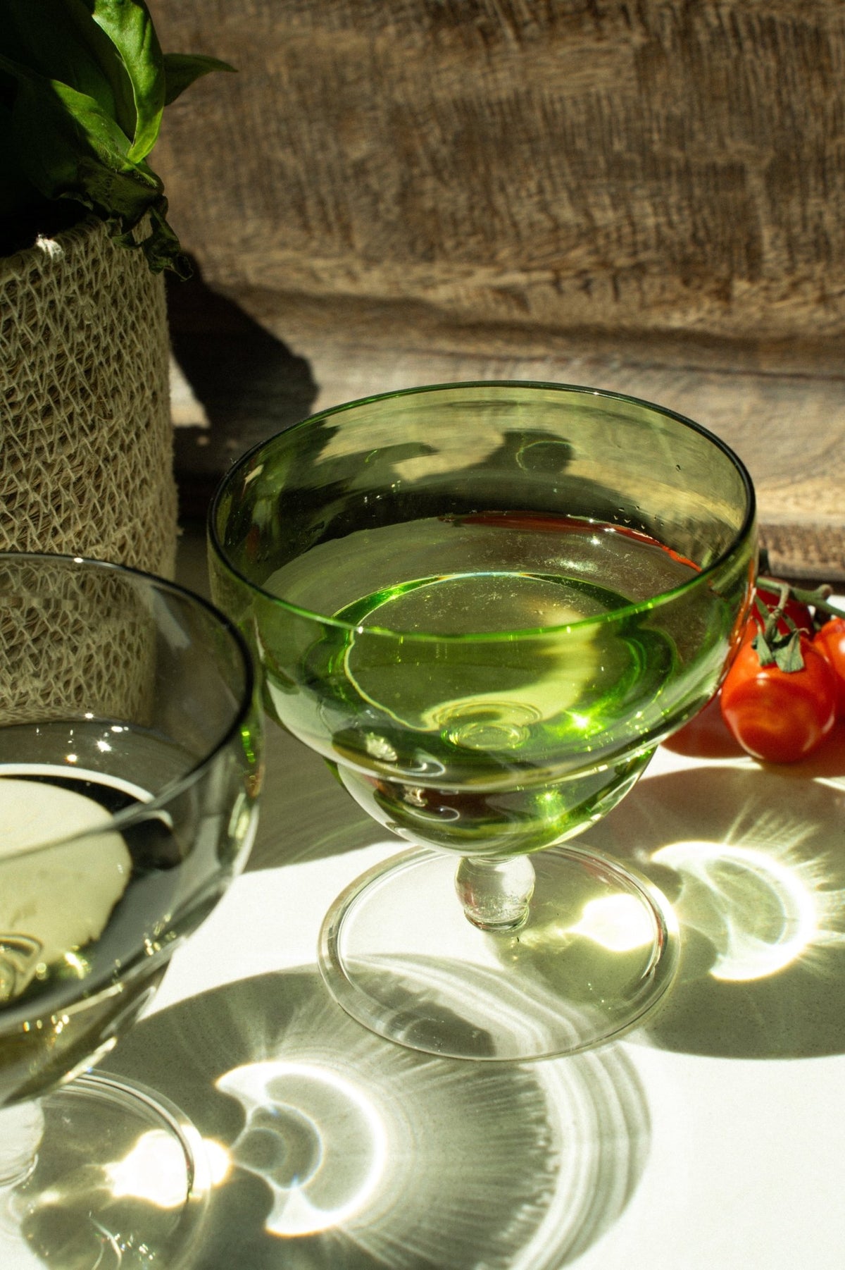 Coupe en verre vert sculptural, pied rond, vue en gros plan.