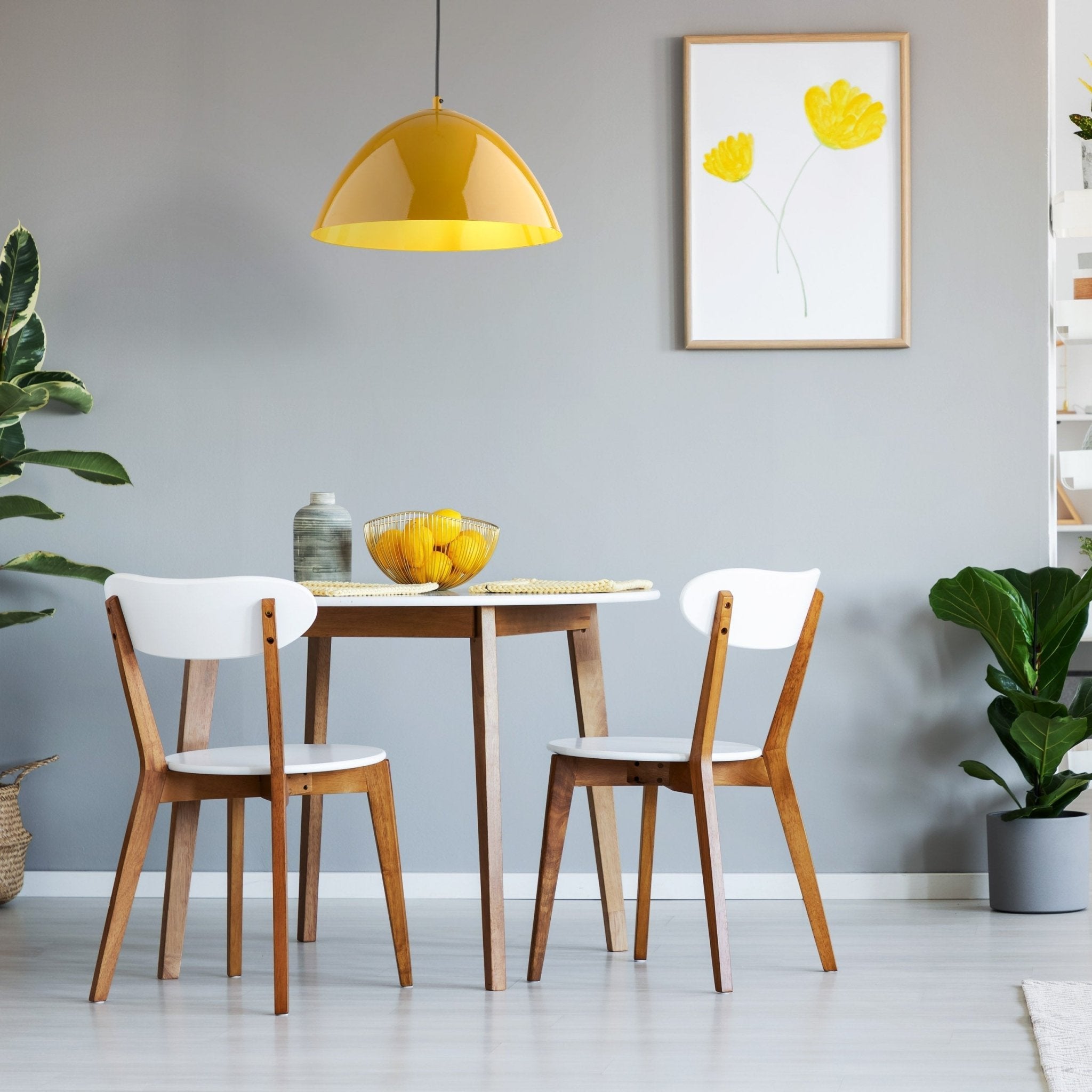 Luminaire suspendu en acier peint jaune, abat-jour hémisphérique au-dessus d’une table