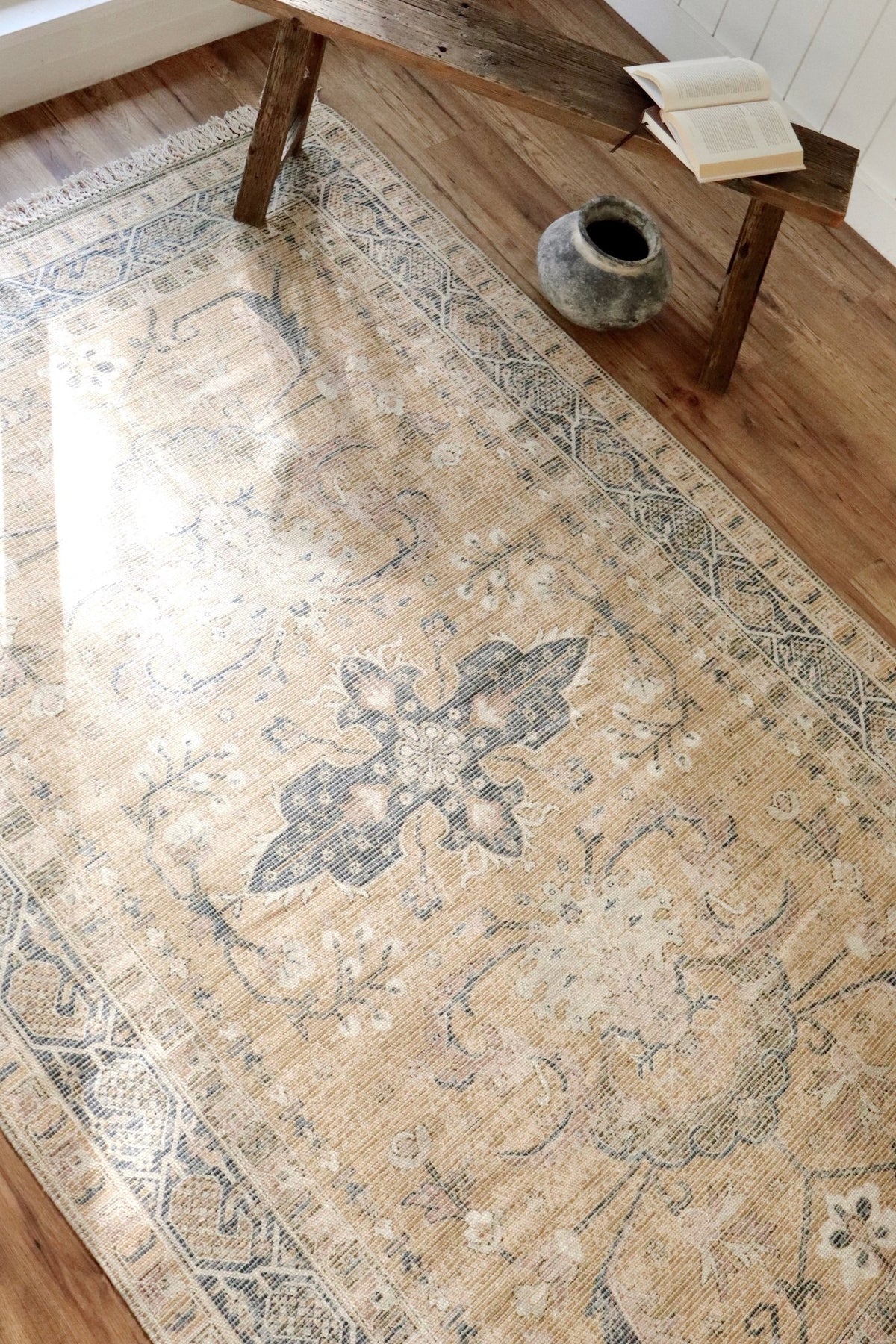 Tapis beige à motifs inspirés turcs, bordure bleue et franges.