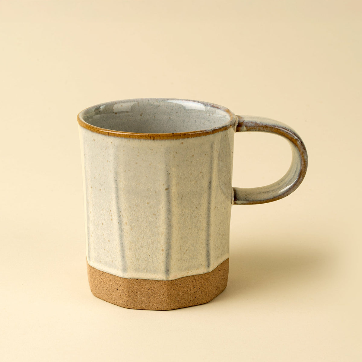 Tasse en grès gris clair et beige, finition granuleuse, anse ronde.